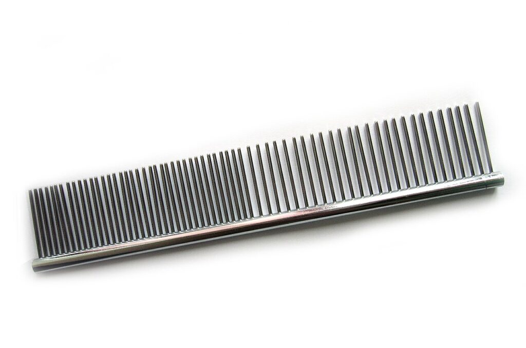 A metal grooming comb with closely and widely spaced teeth on a white background.